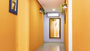 A hallway with yellow walls, a wooden floor, and a door at the end. - Hostal Rober (Madrid)