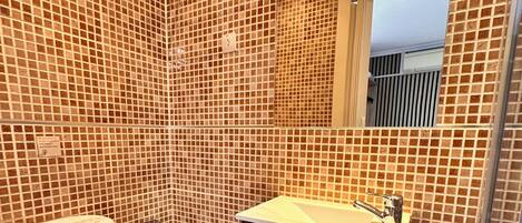 A bathroom with a toilet, sink, and shower area.