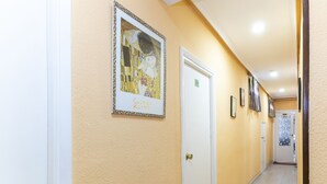 A hallway with a framed artwork, a door, and a corridor leading to another room. - Hostal Rober (Madrid)
