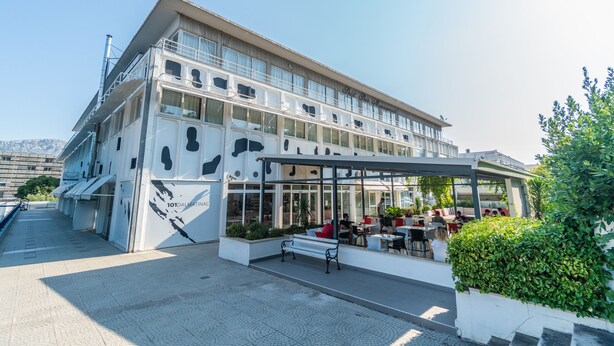 A modern building with a covered outdoor seating area and a large window display. - Design Hostel 101Dalmatinac (Split)