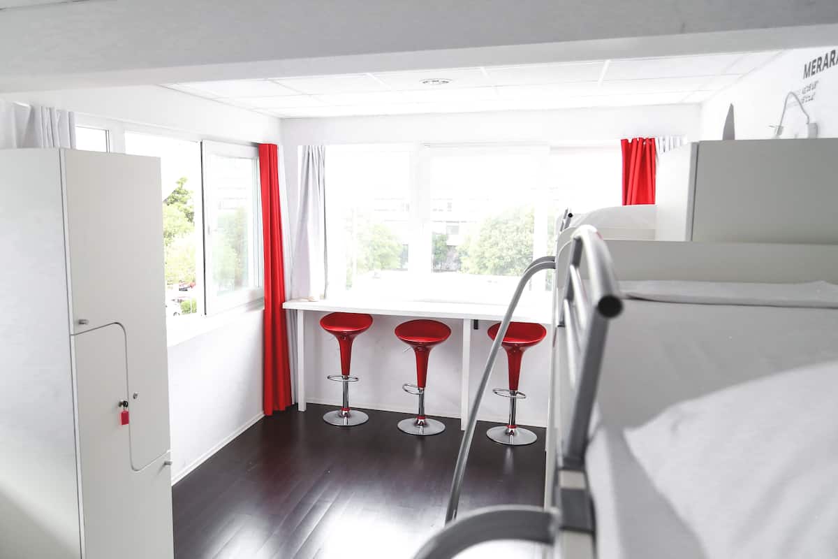 Ein Hotelzimmer mit einem Bett, einem Schreibtisch und drei roten Barhocker.