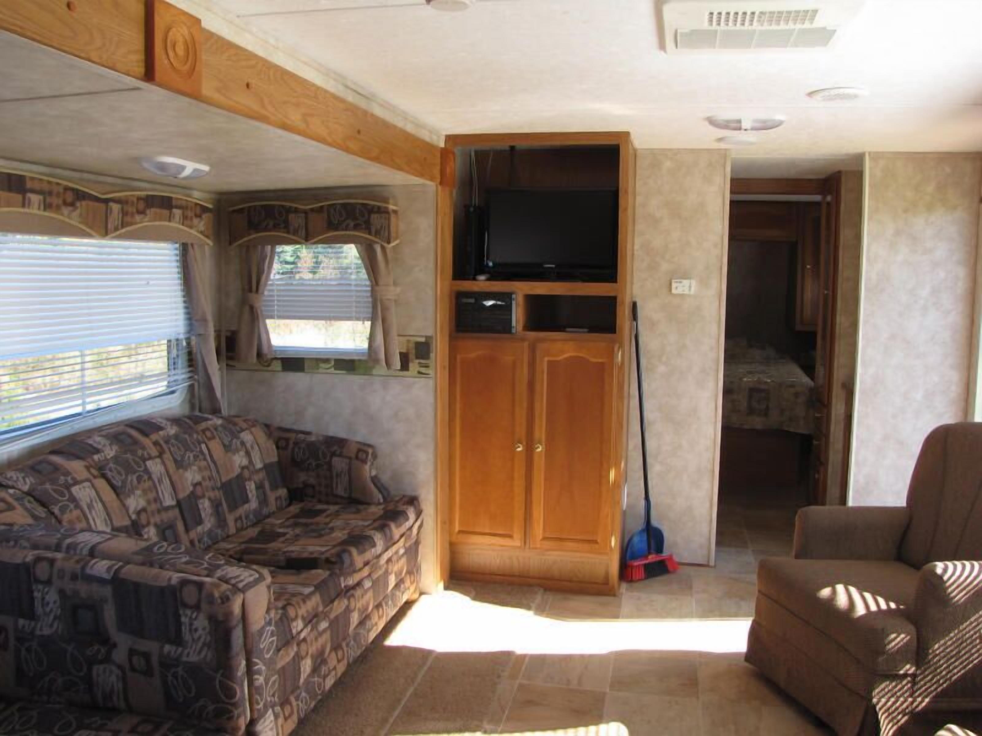 A compact RV interior with a sofa, a television, and a cabinet.