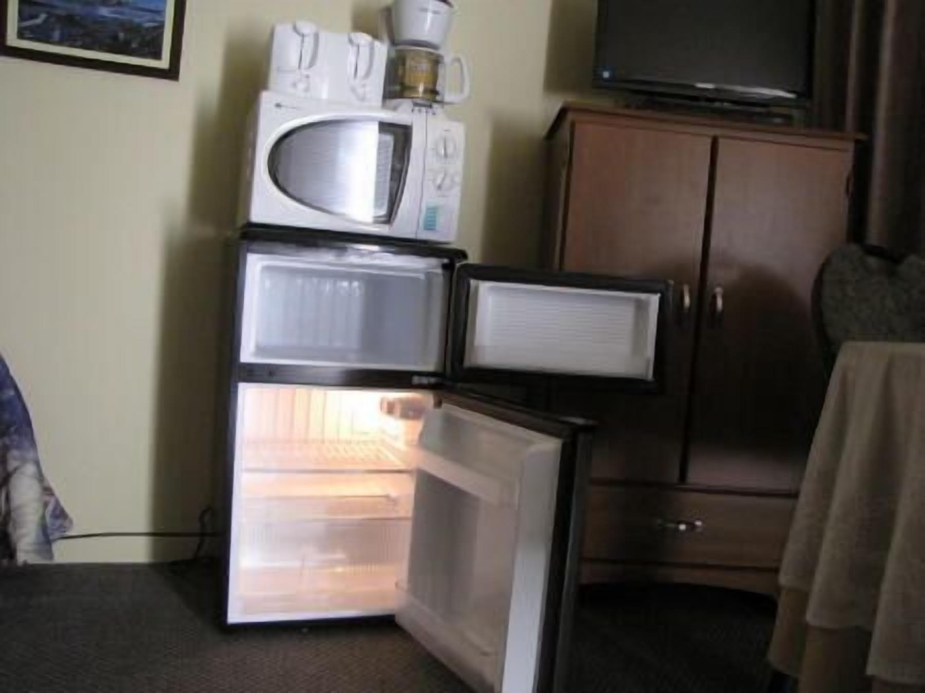 Una kitchenette compacta con microondas, cafetera y refrigerador.