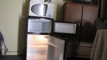 Una kitchenette compacta con microondas, cafetera y refrigerador.