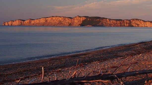 A rocky shoreline with a calm sea and cliffs in the background. - Motel du Haut Phare (Gaspé)