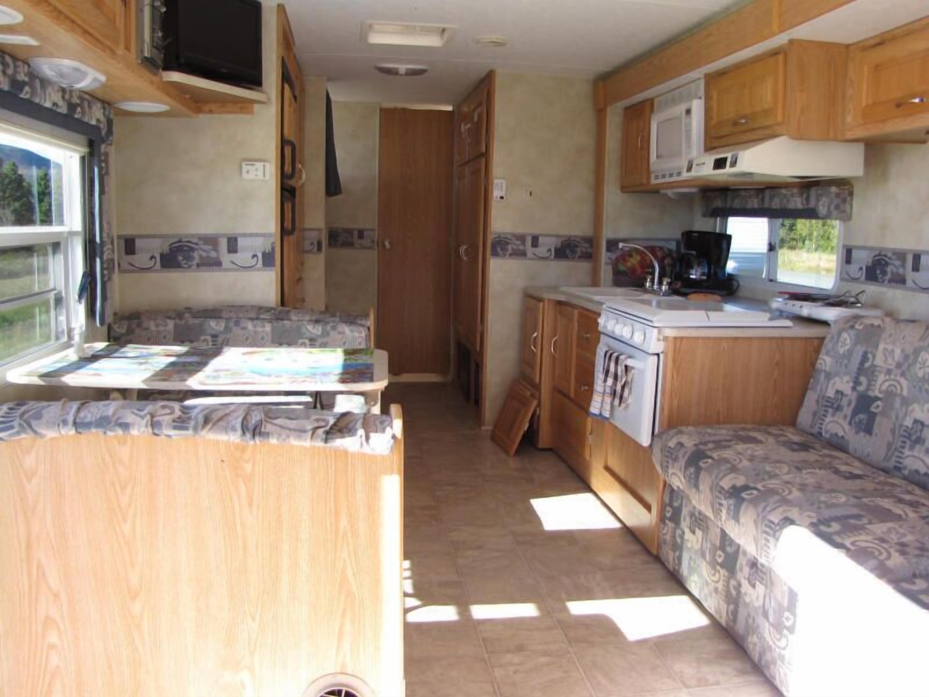 Une cuisine compacte intégrée dans le camping-car, équipée d’une cuisinière, d’un four à micro-ondes et d’un évier. On y trouve également un petit coin repas avec une table et un canapé.