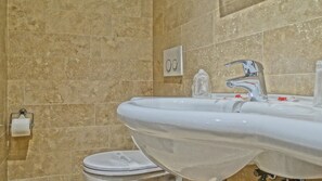 A bathroom with a white sink, a mirror, and a toilet. - Vaticano Royal Suite (Rome)