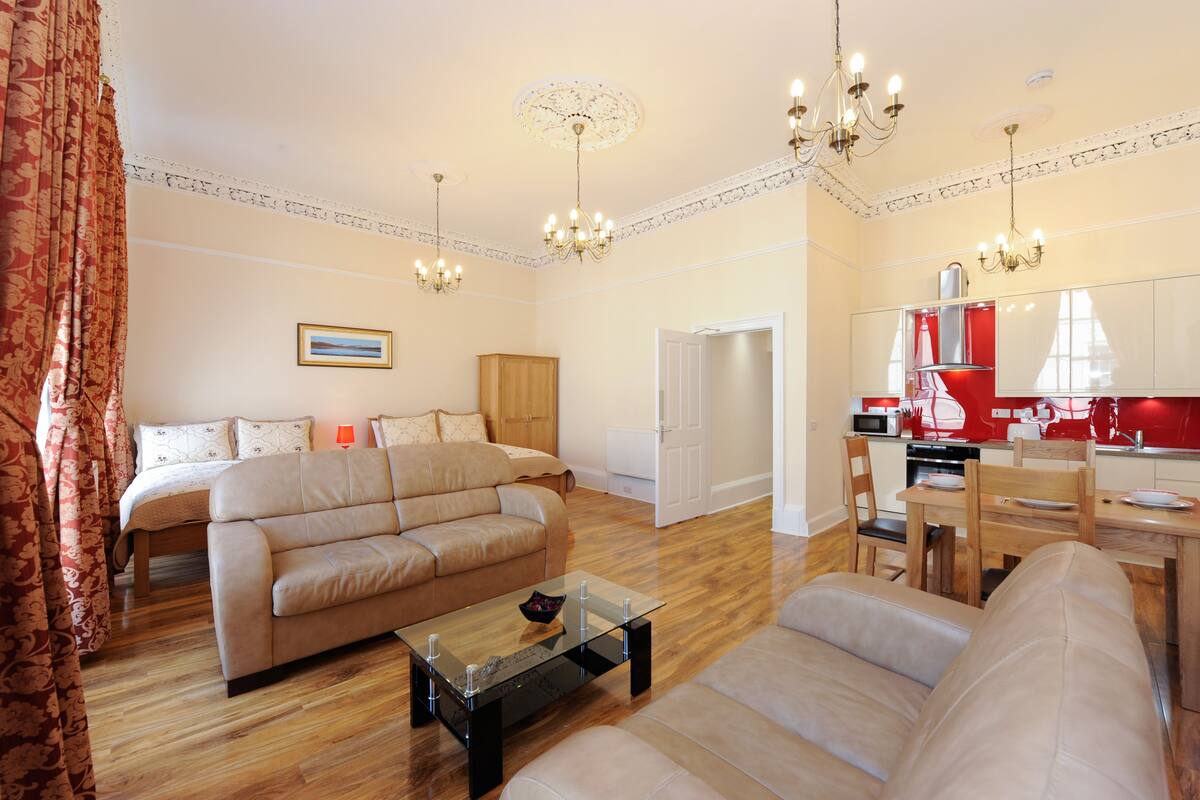 A spacious living room with a sofa, a glass coffee table, and a dining area with a table and chairs.