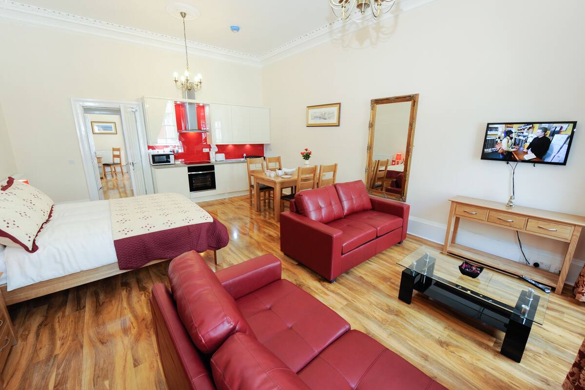 A modern living room with a sofa, a glass coffee table, and a TV.