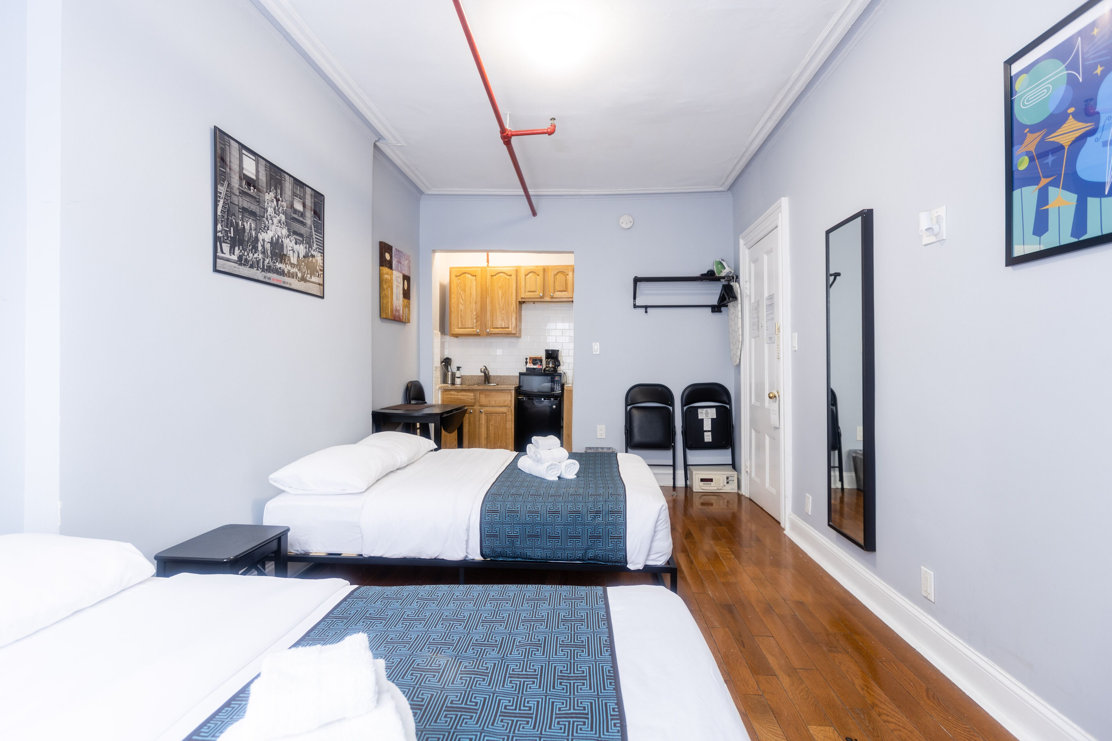 A hotel room with two beds, a kitchenette, and a bathroom.