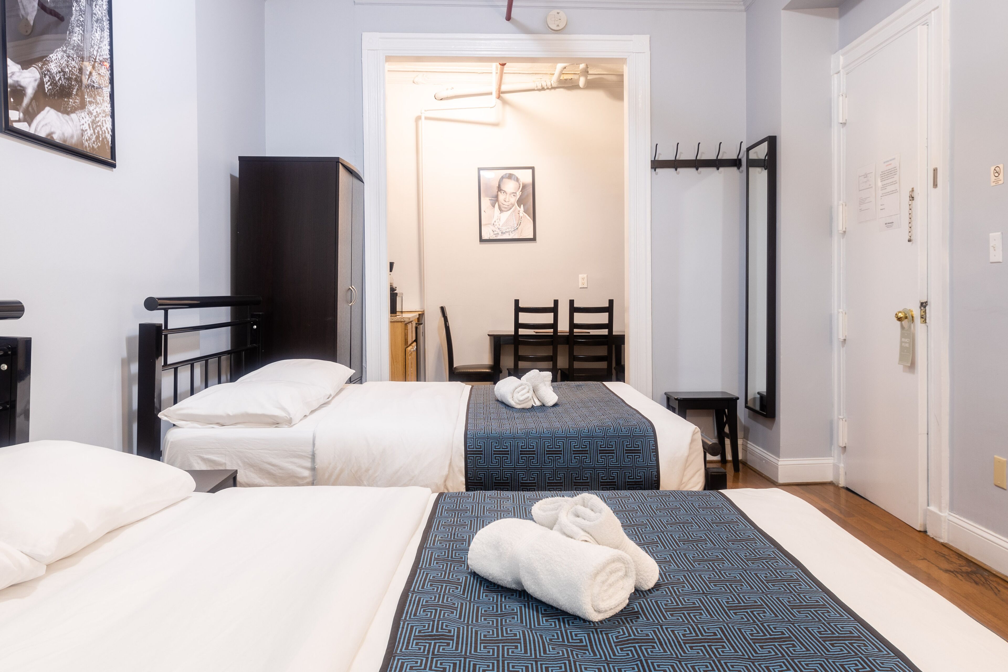 A hotel room with two beds, a desk, a chair, and a wardrobe.