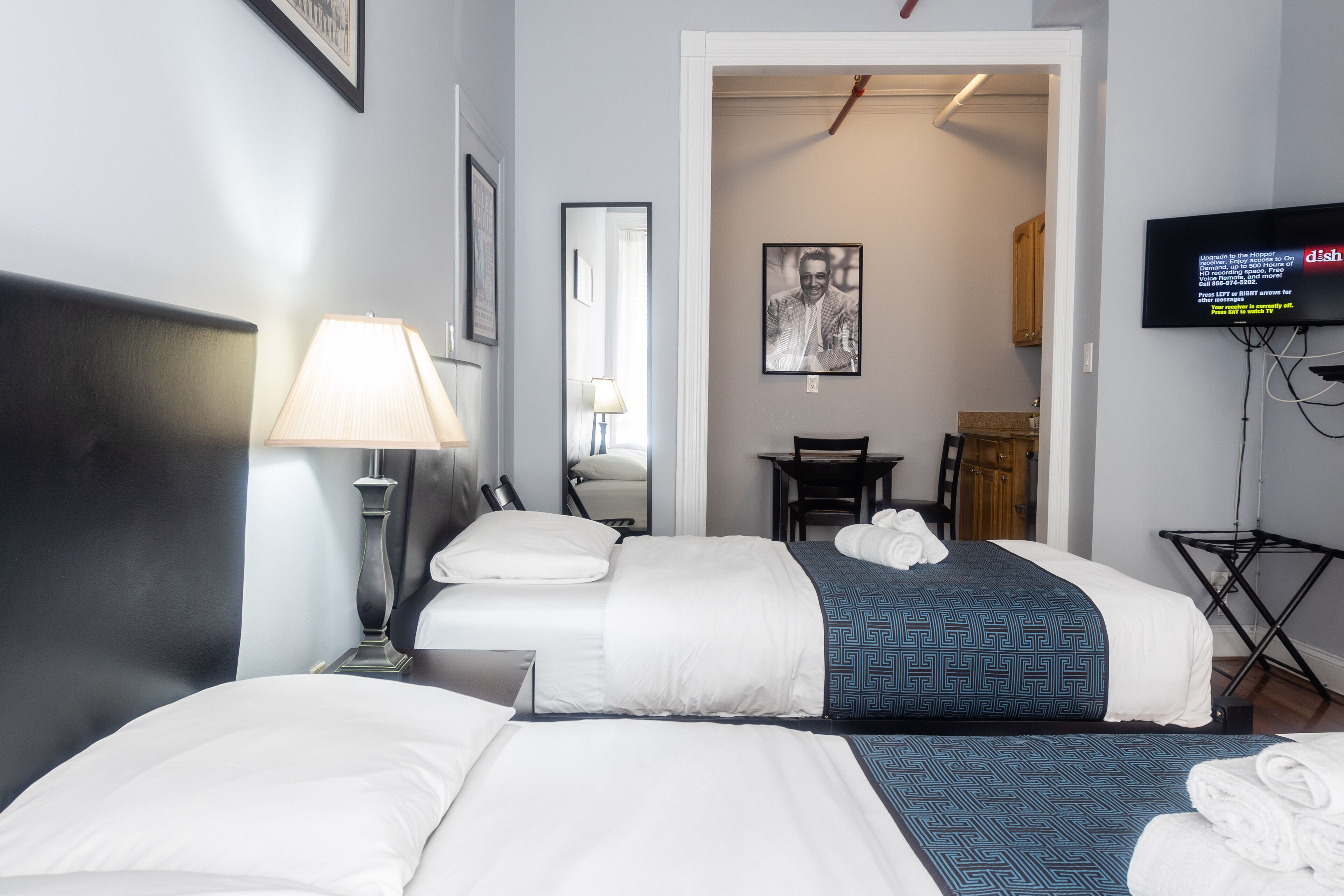 Une chambre d’hôtel avec deux lits, un bureau, une chaise, une télévision et une lampe.
