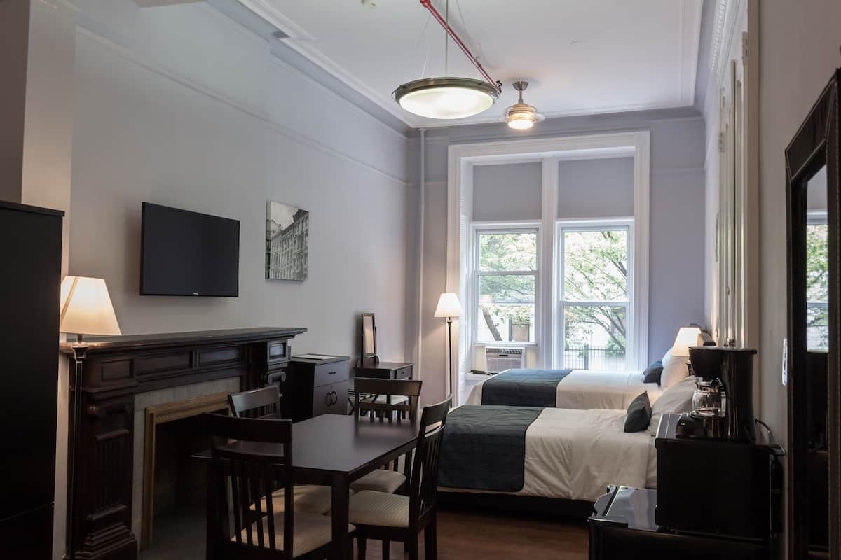 Une chambre d’hôtel équipée d’une table à manger, de deux lits, d’une télévision et d’une cheminée.