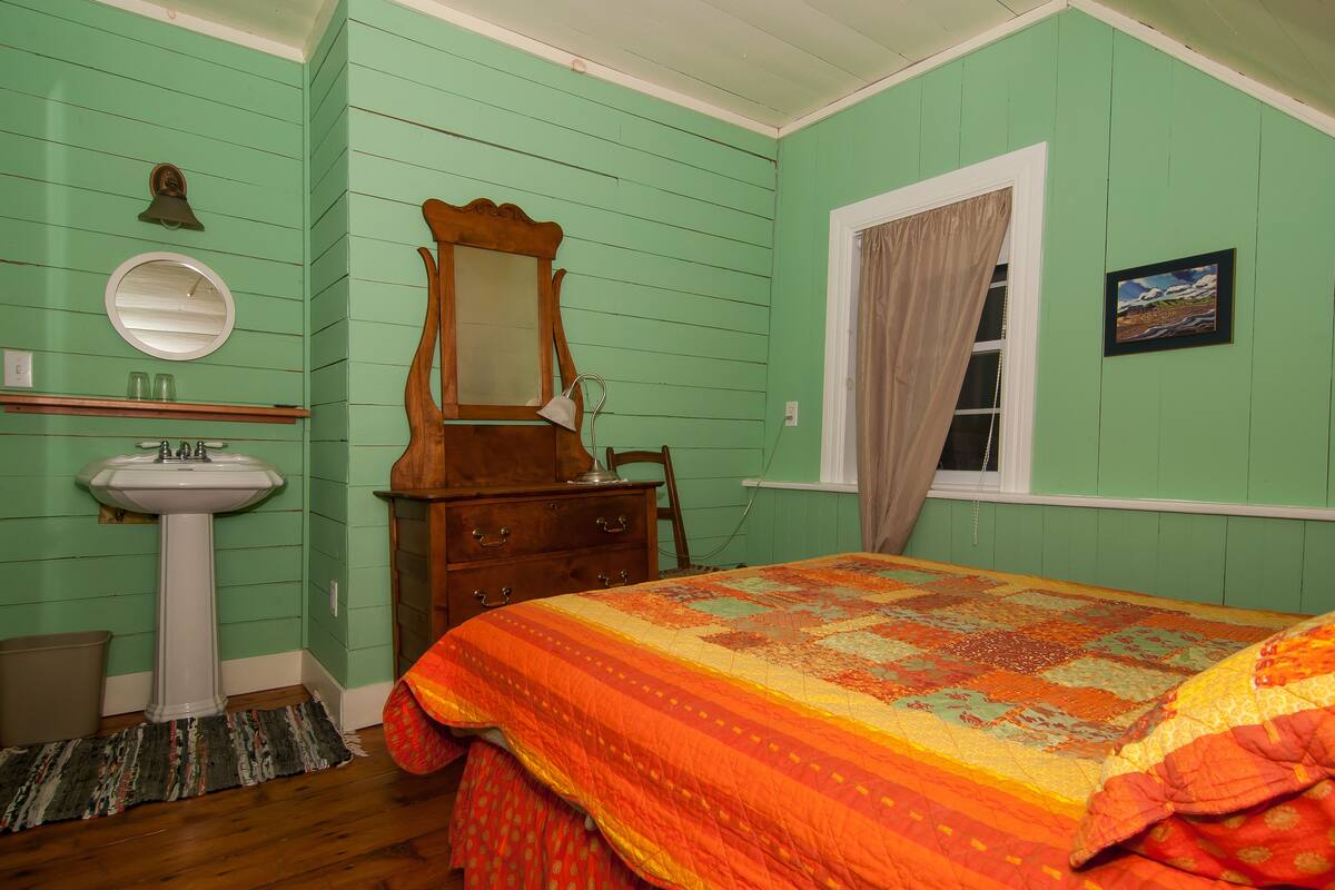 A bedroom with a bed, dresser, and a mirror.