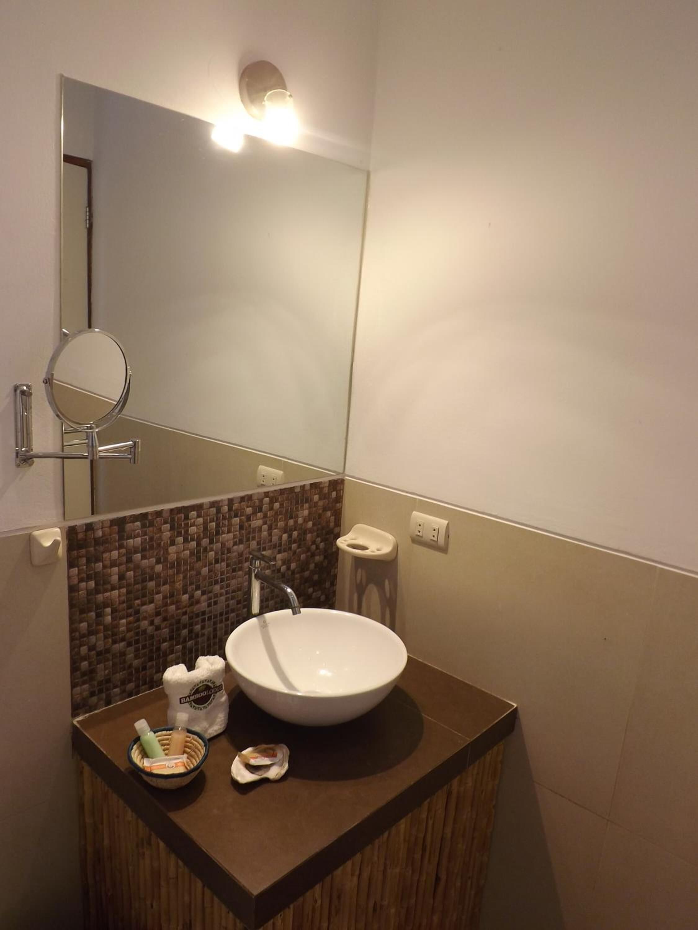 Un baño con un espejo redondo, un lavabo blanco y un taburete pequeño.