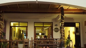 Un área de estar al aire libre con mobiliario de madera y una mesa de comedor, una estatua y un cartel que indica la disponibilidad de WiFi.