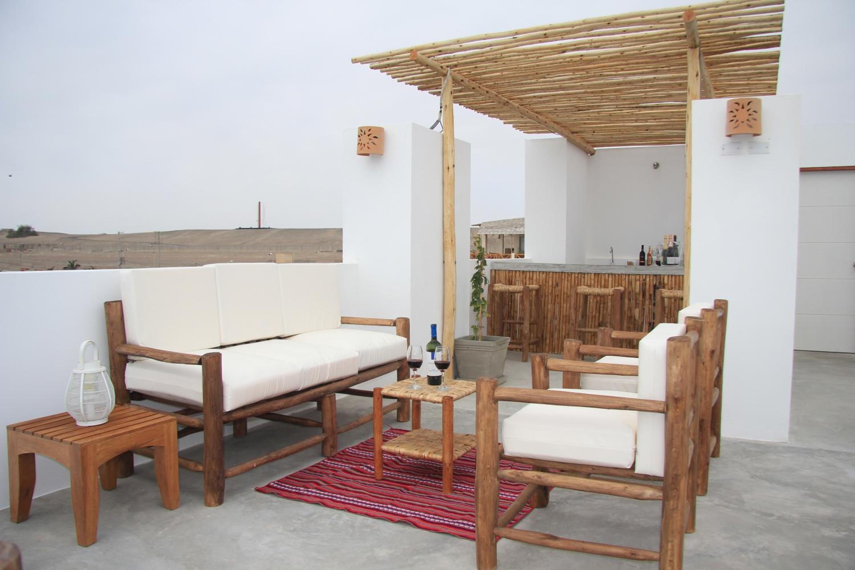 A rooftop terrace with wooden furniture, a bar area, and a view of the landscape.