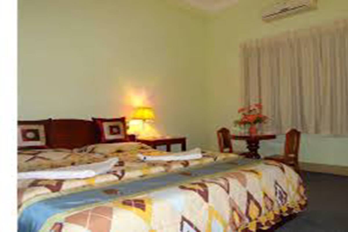 Une chambre d’hôtel avec un lit, un bureau, une lampe et une fenêtre avec des rideaux.