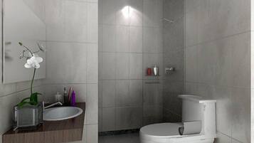 Un baño moderno con inodoro blanco, lavabo con encimera de mármol y zona de ducha.