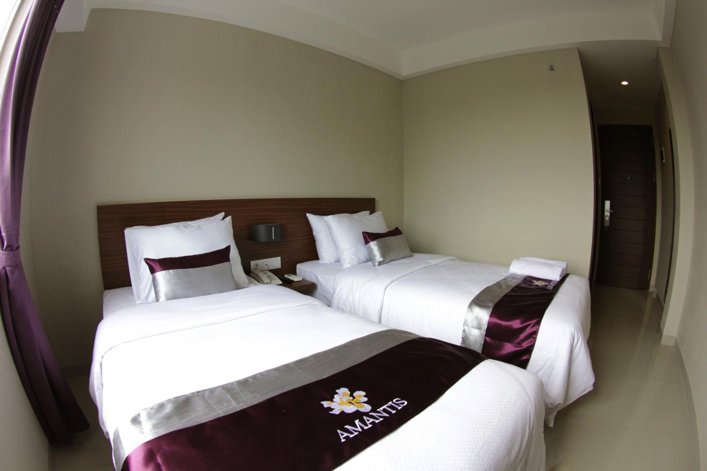 A hotel room with two beds, a wooden headboard, white bedding, and a name tag on the beds.