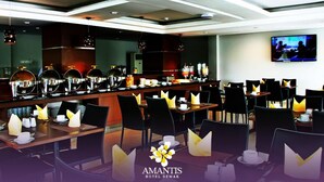 A modern hotel dining area with a long counter, multiple tables, and chairs. - Amantis Hotel (Demak)