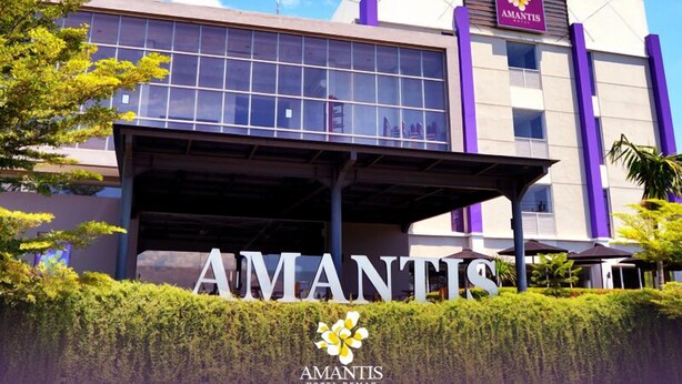 A modern hotel building with a prominent 'AMANTIS' sign, large windows, and a covered entrance area. - Amantis Hotel (Demak)