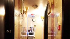 A narrow hallway with a marble floor, a small refrigerator, and a clock on the wall. - Germany Hostel (Kowloon)