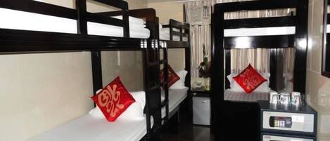 A hotel room with bunk beds, a small desk with a mirror, and a minibar.