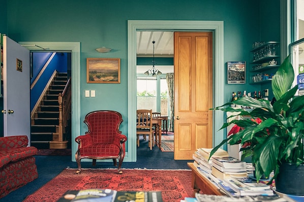 A room with a staircase, a red armchair, a dining area, and a bookshelf. - The Great Ponsonby ArtHotel (Auckland)