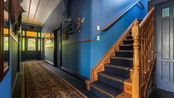 A hallway with a blue wall, a wooden staircase, and a patterned carpet.