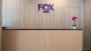 Una recepción con un panel de pared de madera, un letrero del HOTEL FOX y una orquídea en maceta.