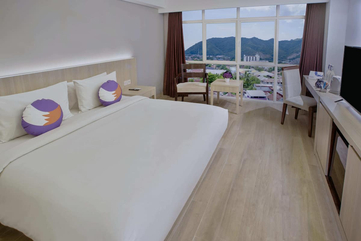 Ein Hotelzimmer mit einem großen Bett, einem Schreibtisch, einem Stuhl und einem Fernseher.