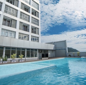 Een modern hotel met een zwembad, grote ramen en uitzicht op de bergen.