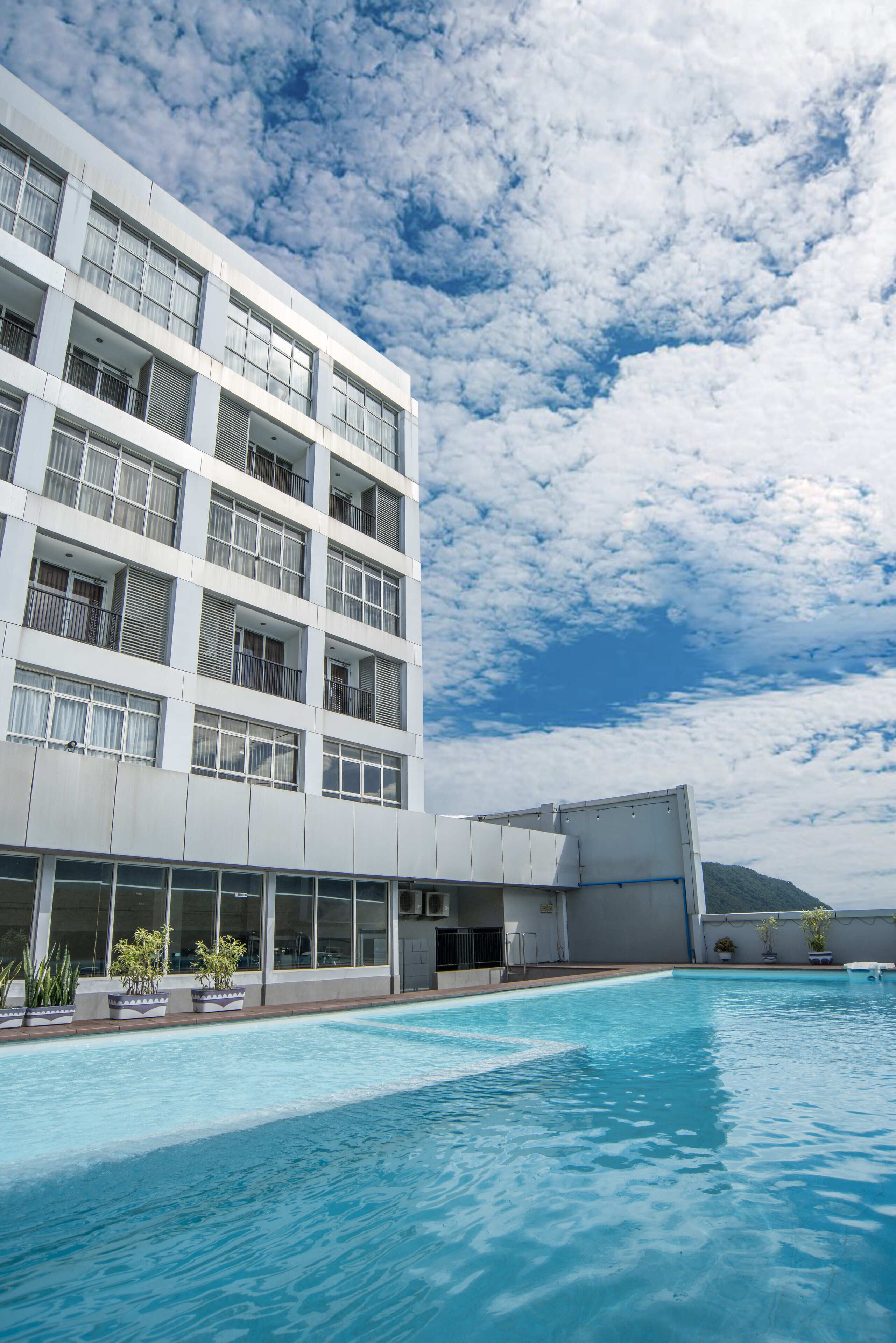 A modern building with a swimming pool, large windows, and balconies.