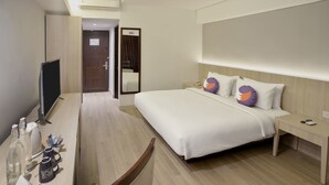 Habitación de hotel con una cama grande, mesitas de noche, un escritorio con silla, televisor y espejo.