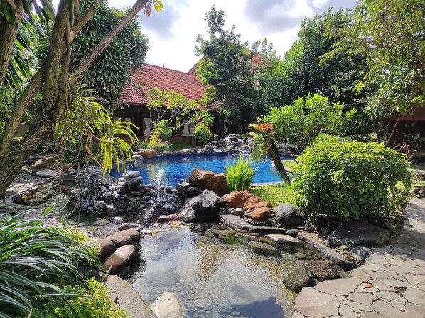 Un jardín con piscina, rocas y una cascada.