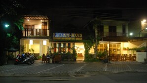 Hotel llamado "SACAN-HUIS", con entrada visible, zona de estar al aire libre y una motocicleta estacionada afuera.