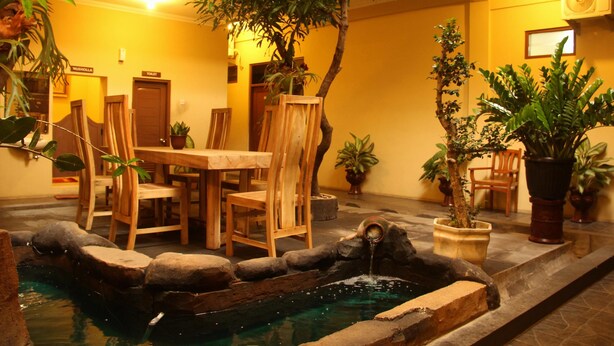 Un patio con piscina, muebles de madera y plantas en macetas.