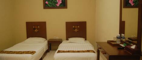 Habitación de hotel con dos camas individuales, cabecera de madera, mesita de noche, escritorio con espejo y una obra de arte floral enmarcada en la pared.