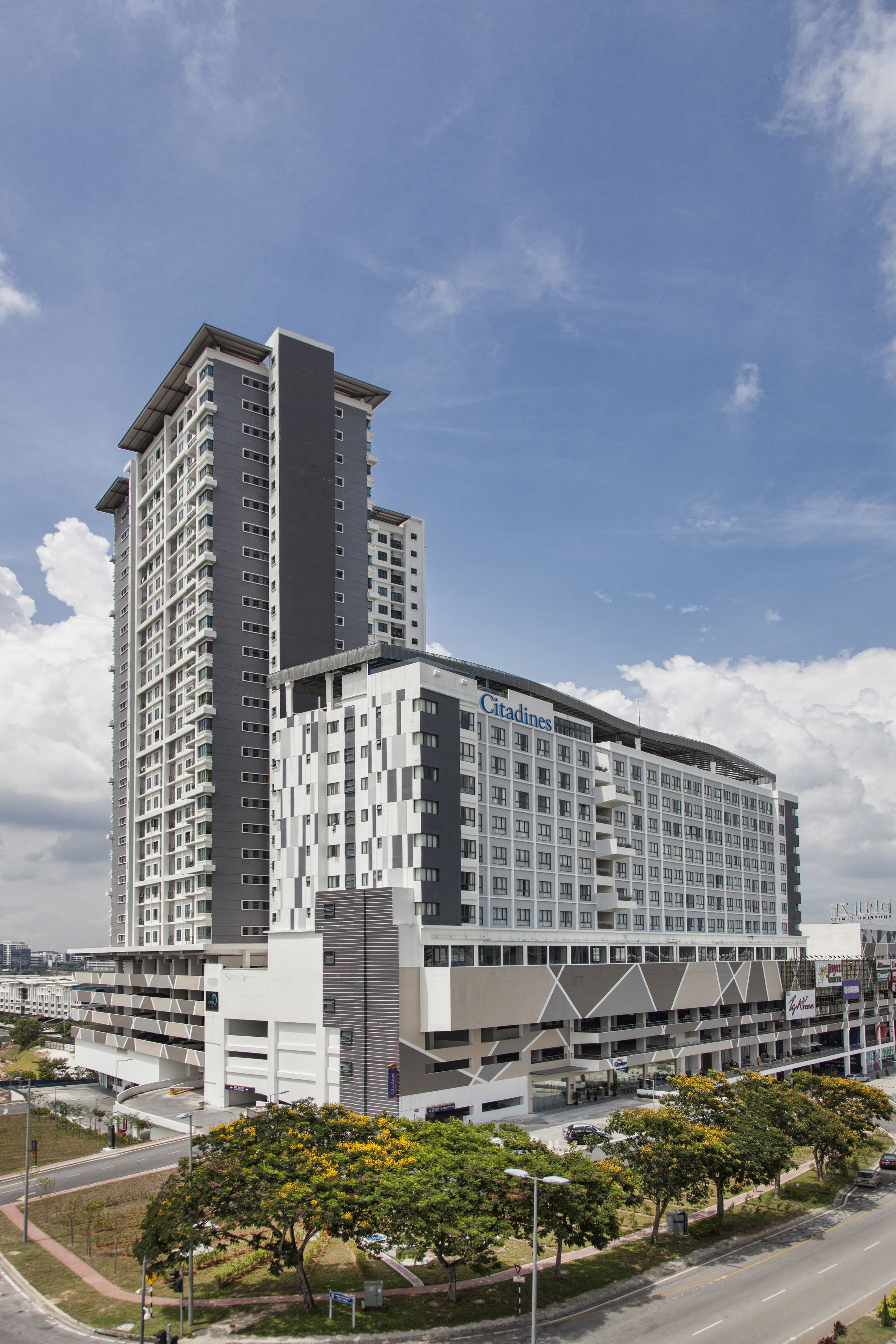 A modern hotel with a prominent vertical tower, multiple floors, and a parking garage.
