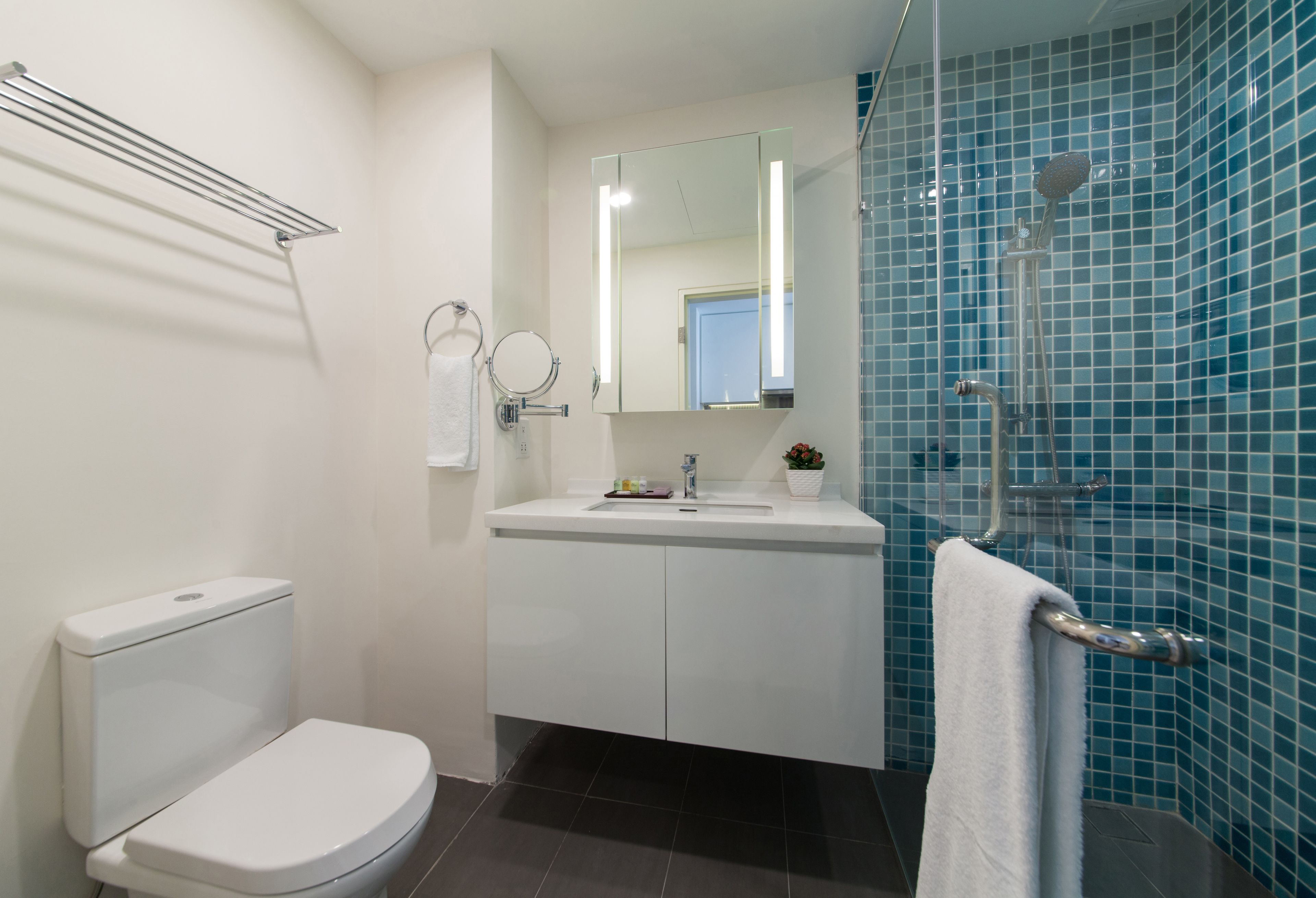 A modern bathroom with a toilet, sink, mirror, and shower.