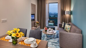 A modern hotel room with a dining area, a sofa, and a TV. - Citadines DPulze Cyberjaya (Cyberjaya)
