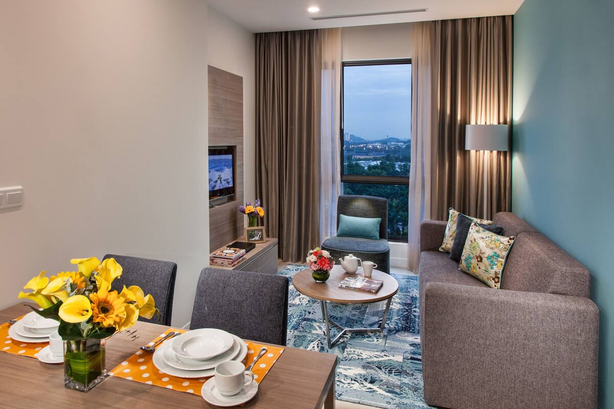 A modern hotel room with a dining area, a sofa, and a TV.