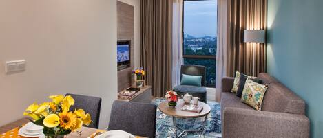 A modern hotel room with a dining area, a sofa, and a TV.