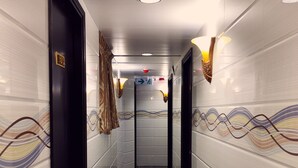 A hallway with a marble floor, white walls with decorative patterns, and black doors. - Manila Hotel - Hostel (Kowloon)