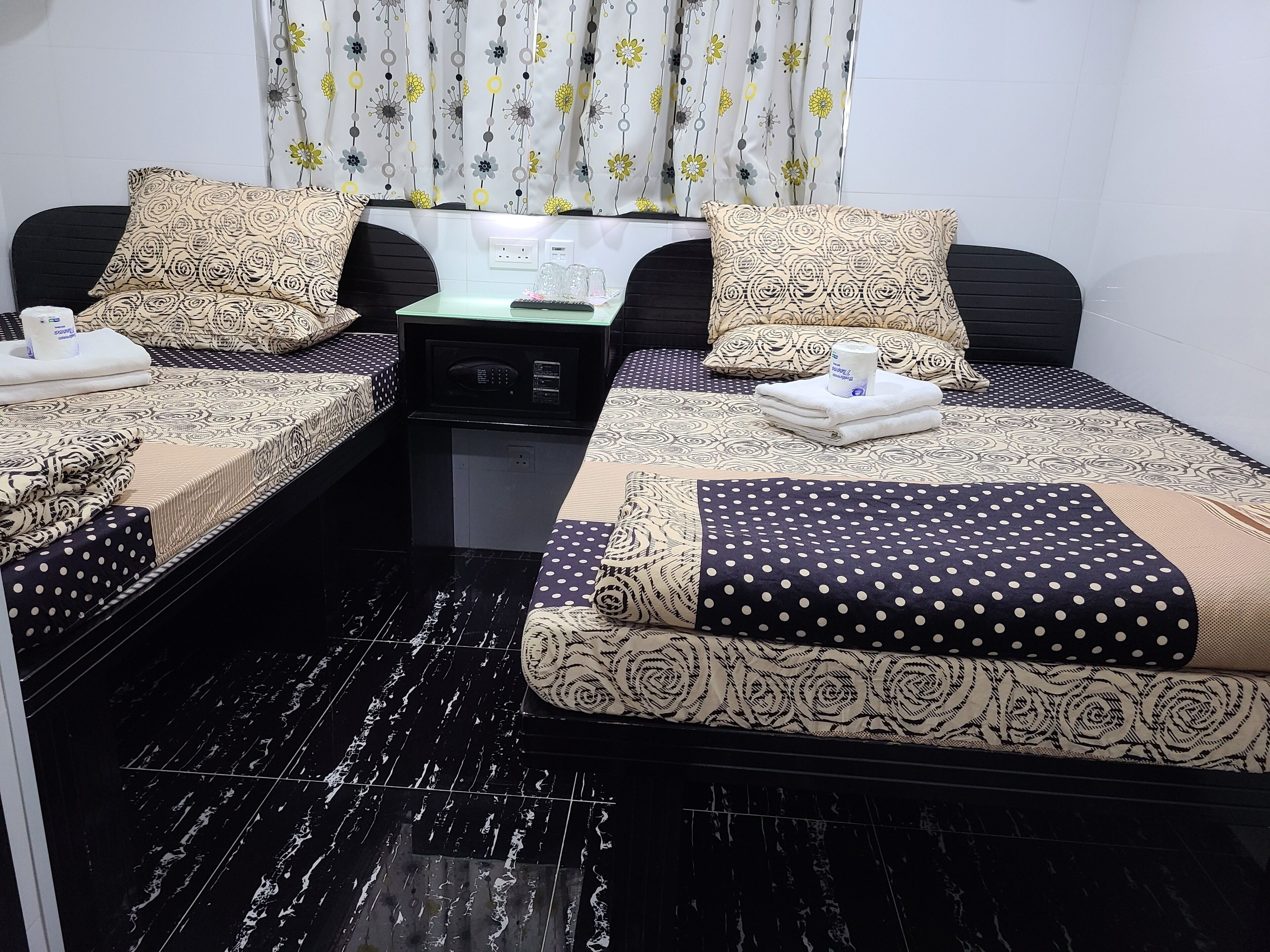 Habitación de hotel con dos camas, una mesita con un microondas y un enchufe.