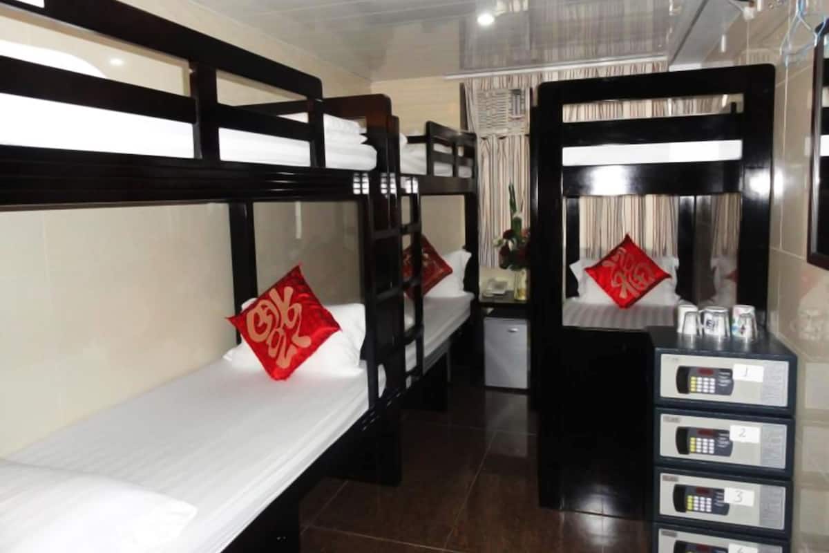 A hotel room with bunk beds, a small desk with a mirror, and a minibar.