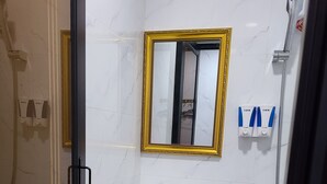 A bathroom with a white sink, a mirror with a gold frame, and a shower area. - Hong Kong Budget Hostel (Kowloon)