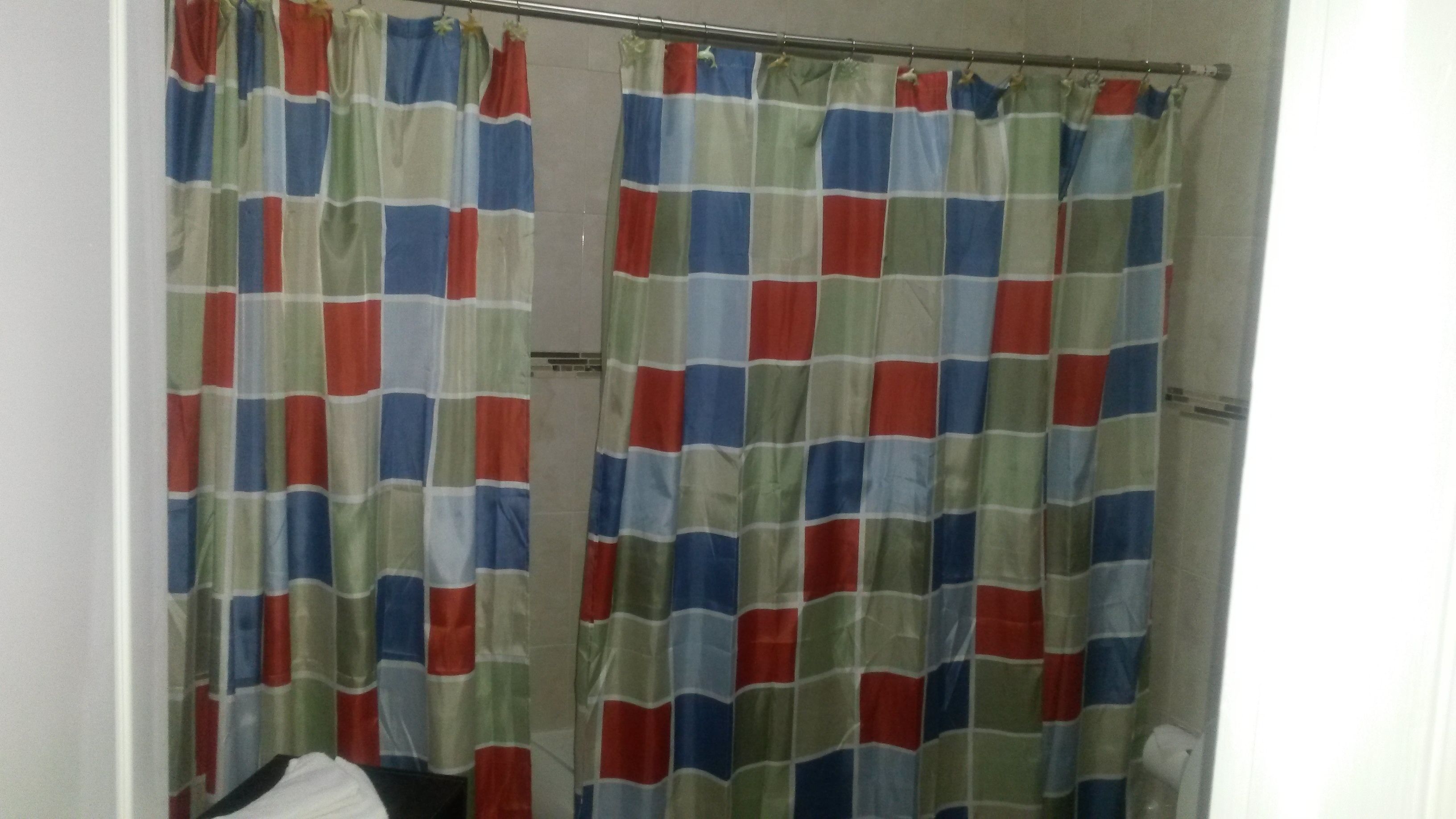Un baño con cortina de ducha estampada con un diseño de cuadros en rojo, verde y azul.