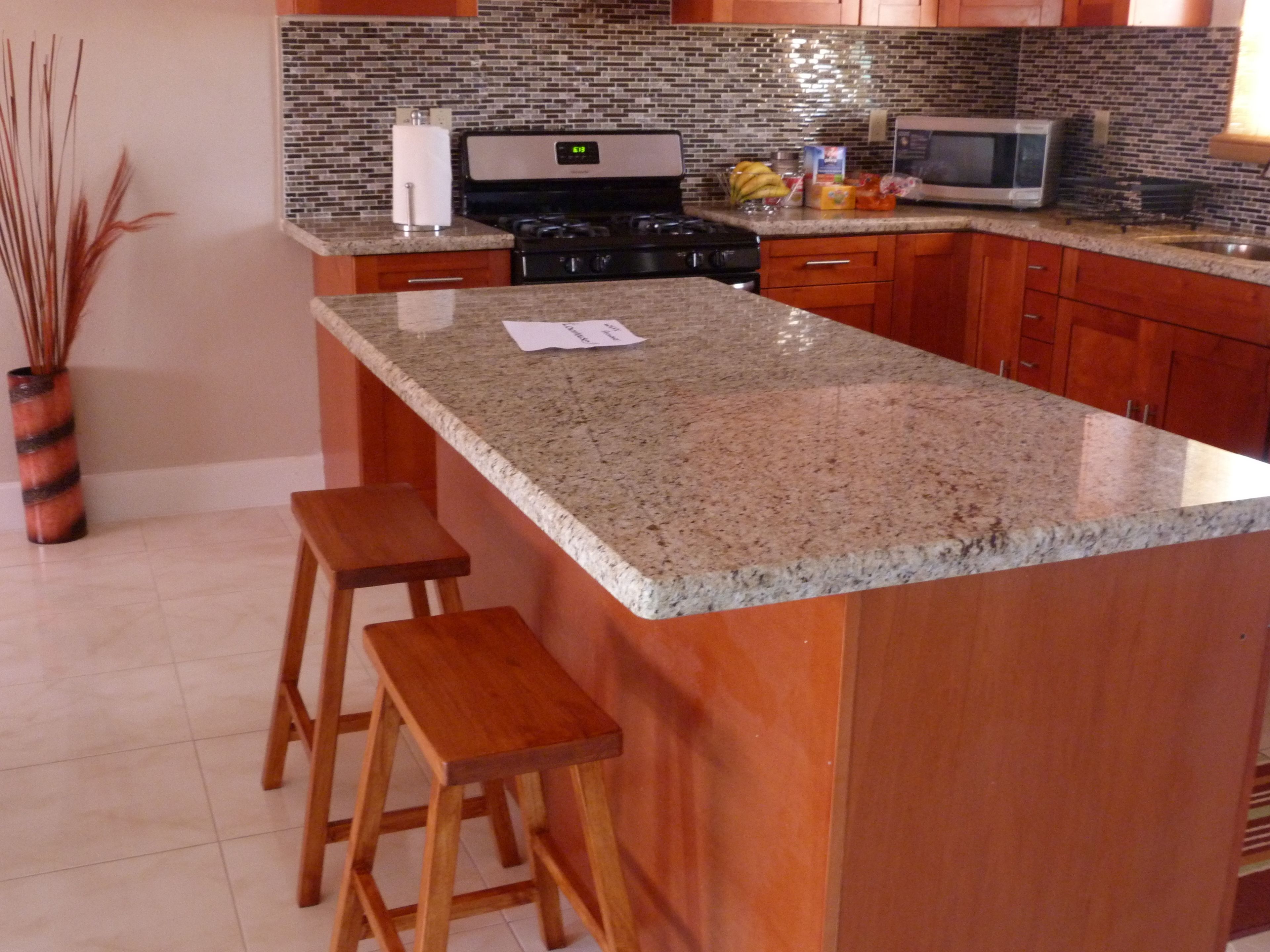 A kitchen with granite countertops, wooden cabinets, a microwave, and a stove.
